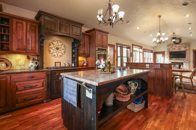 kitchen with an island with sink, a breakfast bar area, open shelves, and a notable chandelier