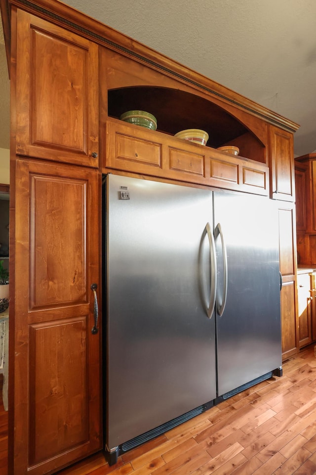 kitchen with light wood-type flooring, brown cabinets, built in refrigerator, and open shelves