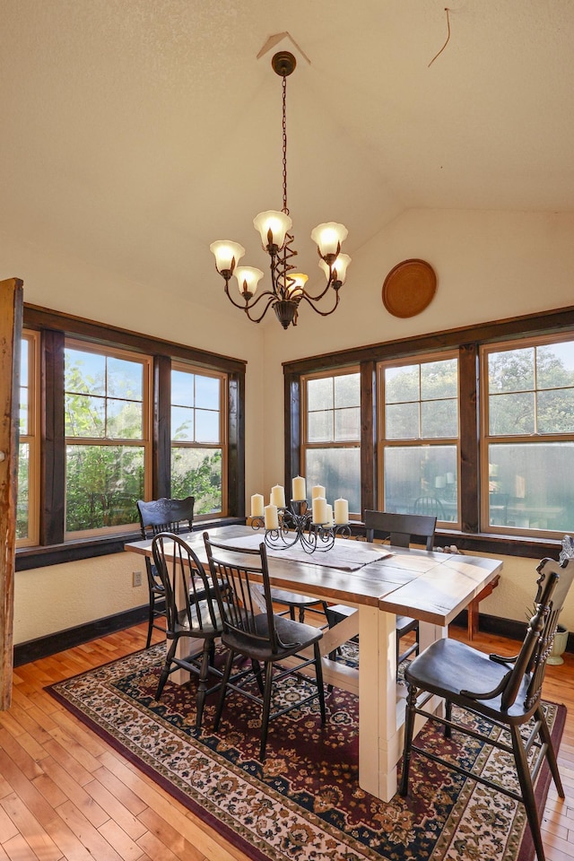 dining area featuring a chandelier, wood finished floors, and lofted ceiling