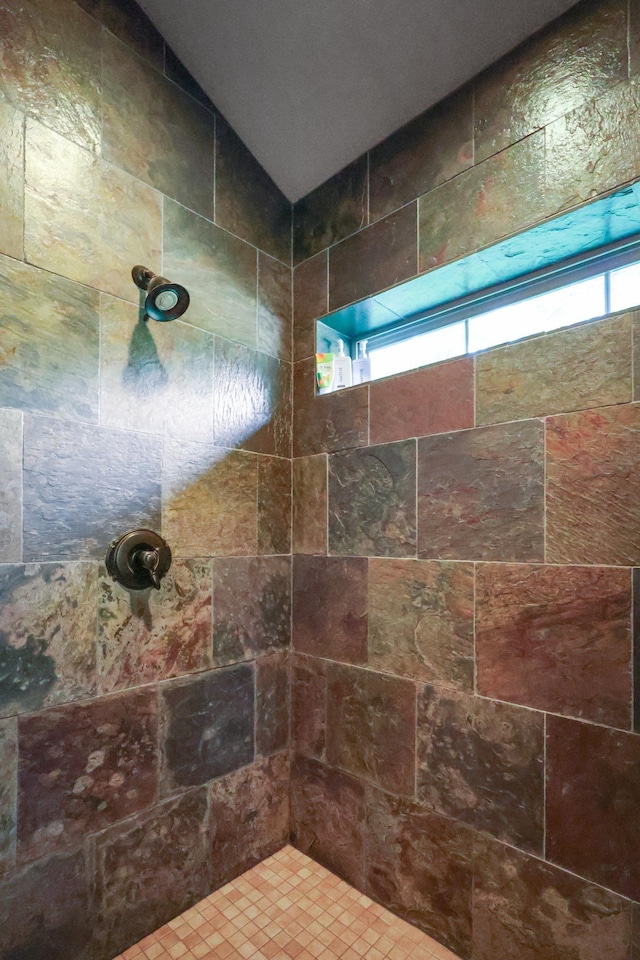 bathroom with vaulted ceiling and tiled shower