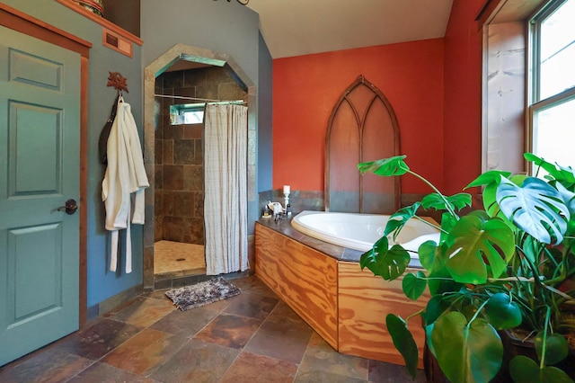 bathroom with a shower stall, a bath, and stone finish flooring