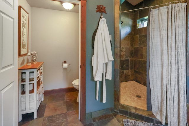 bathroom with stone finish flooring, baseboards, a shower stall, and toilet