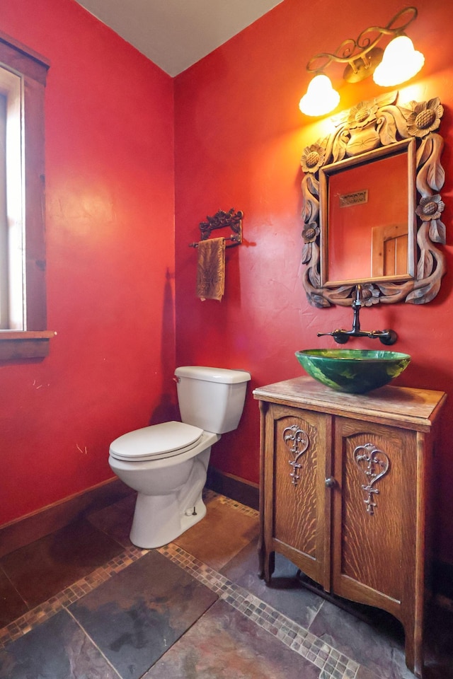 bathroom featuring toilet, vanity, and baseboards