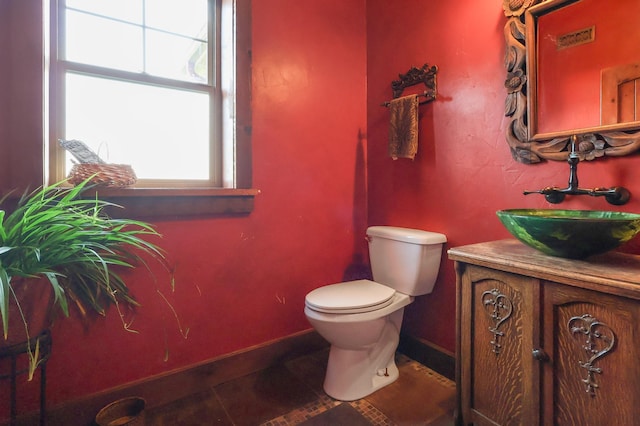 half bathroom featuring tile patterned flooring, baseboards, vanity, and toilet