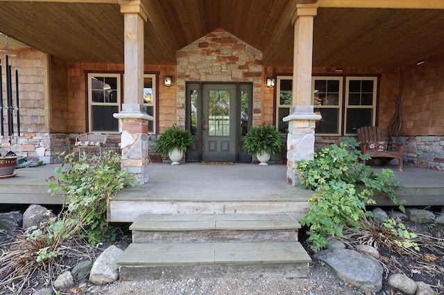 view of exterior entry with covered porch and stone siding