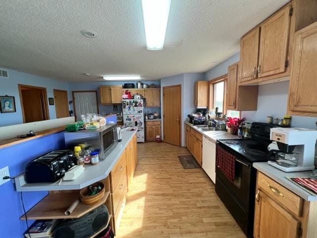 kitchen with light wood-type flooring, a textured ceiling, white appliances, and sink