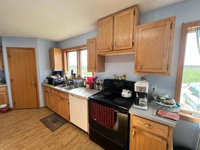 kitchen with light wood-type flooring, dishwasher, a textured ceiling, black range with electric stovetop, and sink