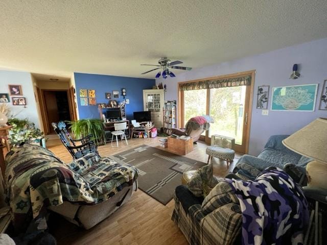 living room with light wood-type flooring, a textured ceiling, and ceiling fan