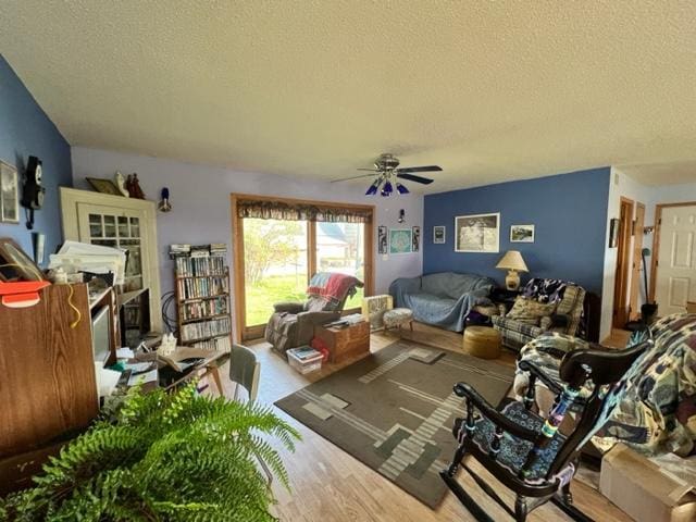 living room with a textured ceiling, wood-type flooring, and ceiling fan