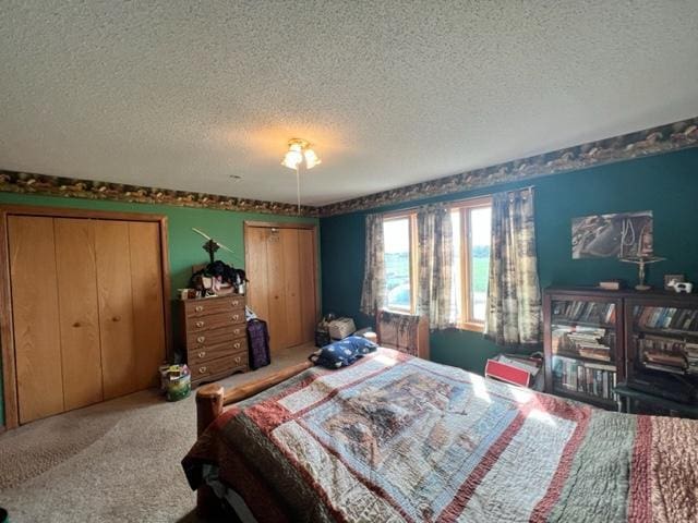 carpeted bedroom with a textured ceiling and two closets