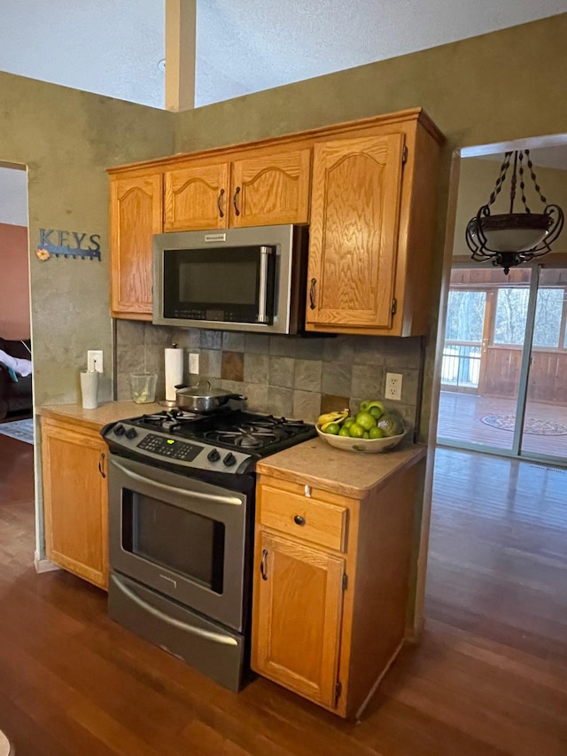 kitchen with stainless steel appliances, dark wood-type flooring, and backsplash