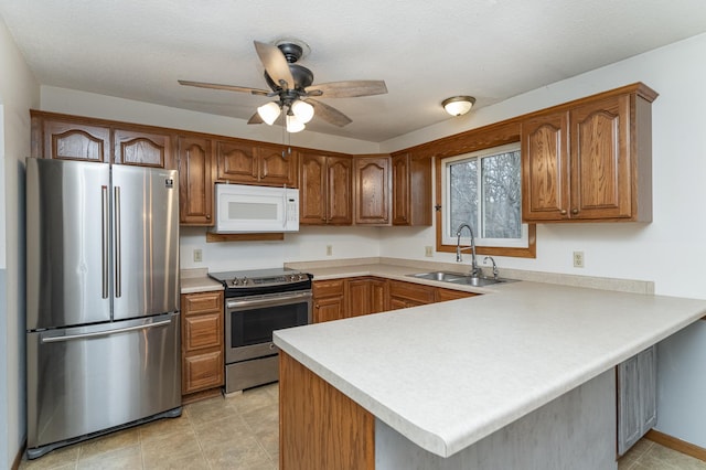 kitchen featuring kitchen peninsula, a textured ceiling, stainless steel appliances, and sink