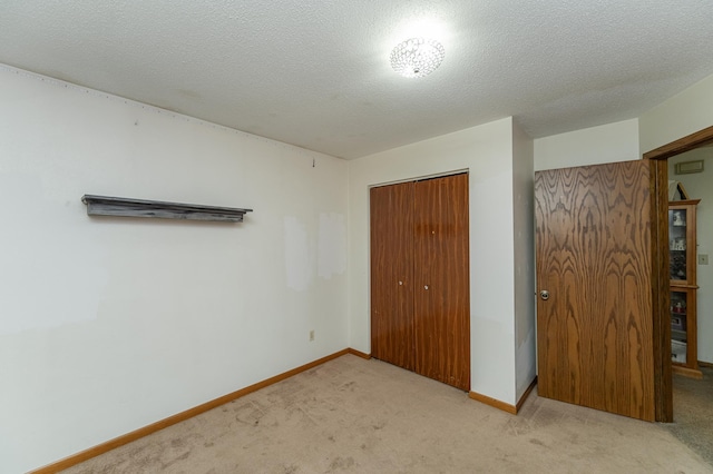 unfurnished bedroom featuring a textured ceiling, light carpet, and a closet