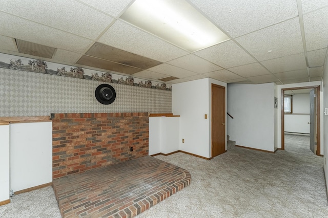 basement with light carpet, a drop ceiling, and a baseboard radiator