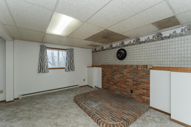 basement with a paneled ceiling, light colored carpet, and a baseboard heating unit