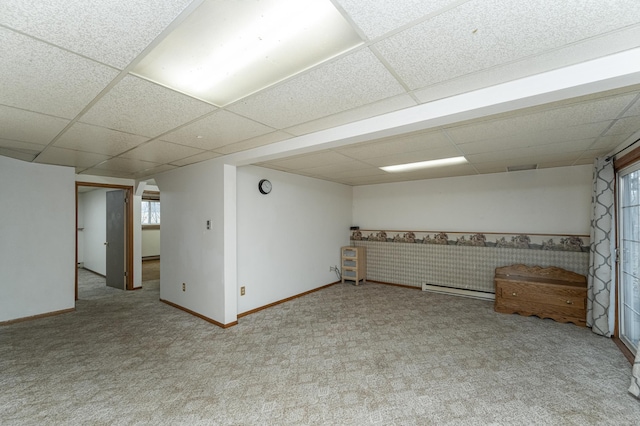 basement with a drop ceiling, a healthy amount of sunlight, light carpet, and a baseboard radiator