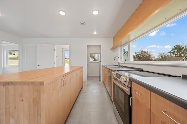 kitchen featuring wooden counters, appliances with stainless steel finishes, a center island, and sink