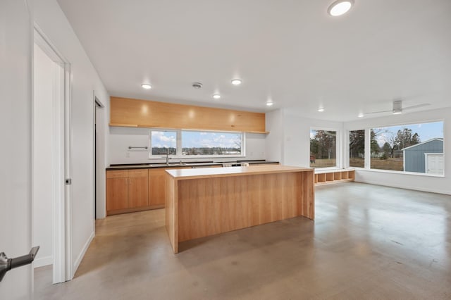 kitchen with ceiling fan, a center island, and sink