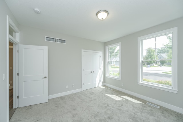 unfurnished bedroom with multiple windows and light colored carpet