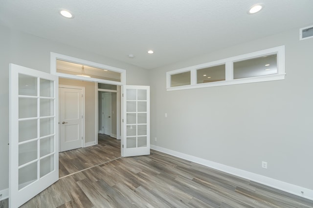 unfurnished bedroom featuring a textured ceiling, wood-type flooring, and french doors