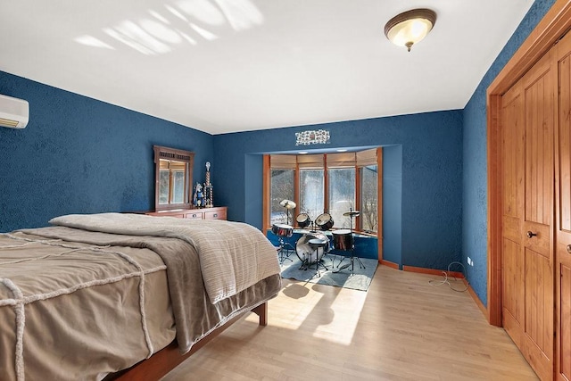 bedroom featuring a wall mounted air conditioner and light hardwood / wood-style floors