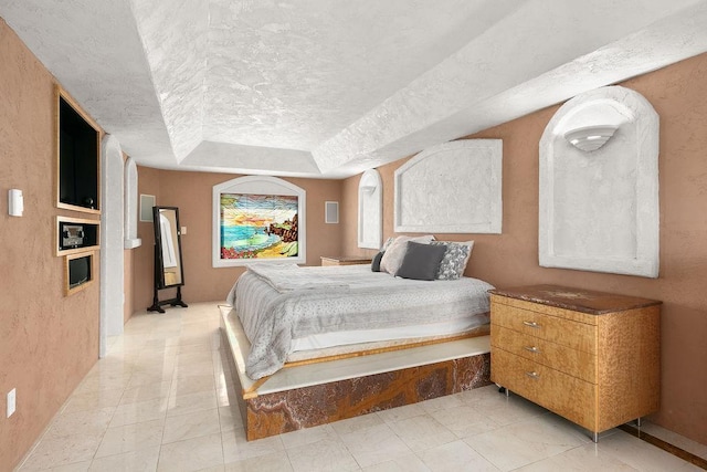 bedroom with a textured ceiling, a raised ceiling, and light tile patterned flooring