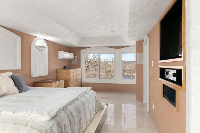 bedroom with a textured ceiling, a raised ceiling, light tile patterned flooring, and a wall mounted air conditioner