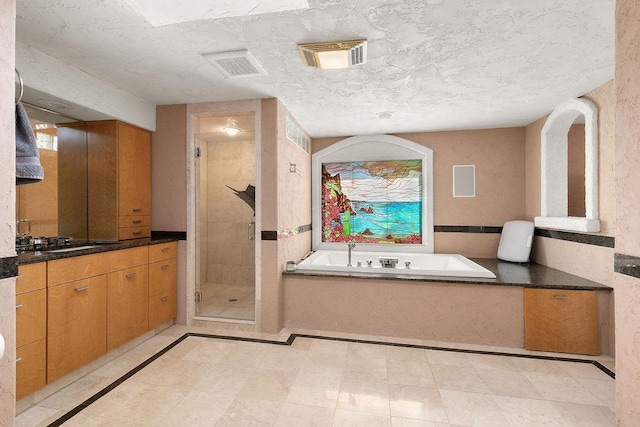 bathroom with independent shower and bath, vanity, and a textured ceiling