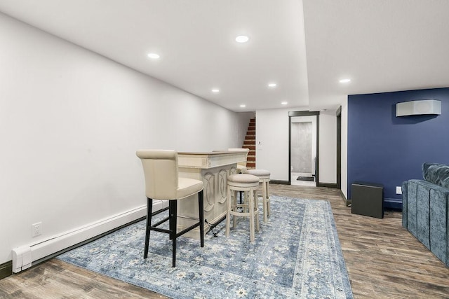 dining space with baseboard heating, indoor bar, and hardwood / wood-style flooring