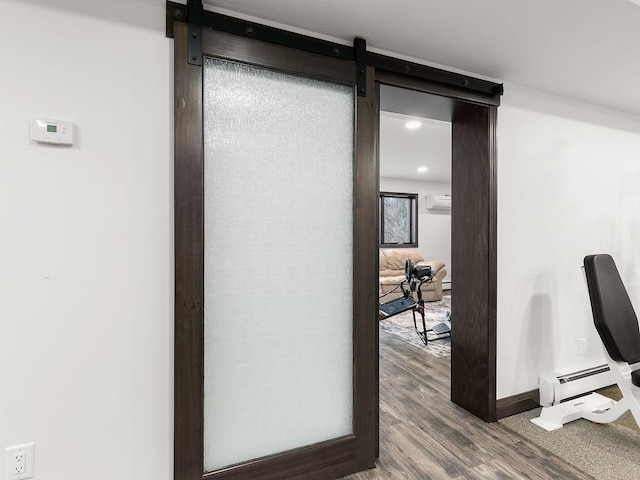 interior space featuring baseboard heating, hardwood / wood-style flooring, and a barn door