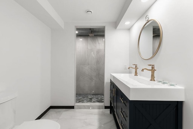 bathroom featuring a tile shower, vanity, and toilet