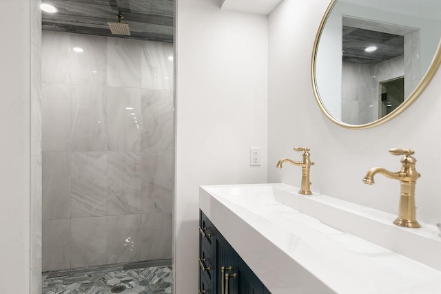 bathroom with a tile shower and vanity