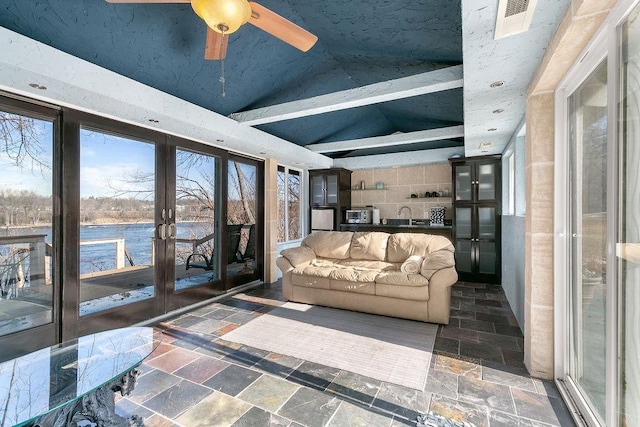 sunroom featuring a water view, lofted ceiling with beams, ceiling fan, and french doors