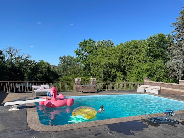 view of swimming pool featuring a patio area and a diving board