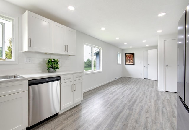 kitchen with stainless steel dishwasher, white cabinets, and a wealth of natural light