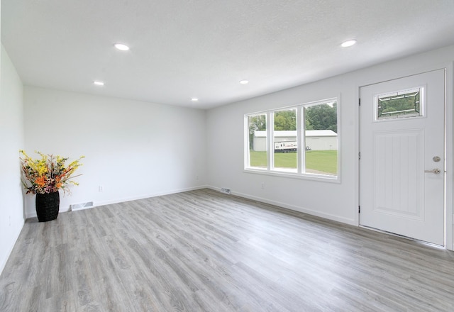 entryway with light wood-type flooring and a textured ceiling