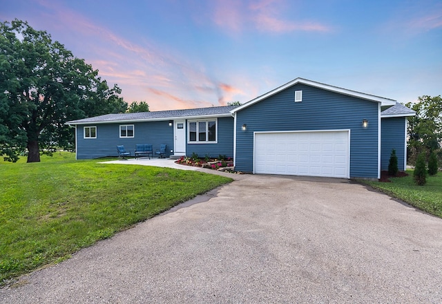 ranch-style home featuring a garage and a yard