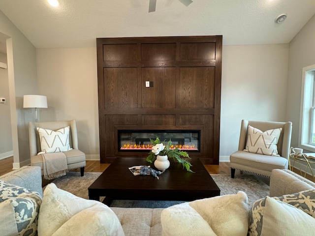 living room featuring a glass covered fireplace, wood finished floors, and baseboards