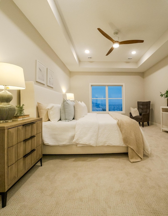 bedroom featuring baseboards, a tray ceiling, recessed lighting, ceiling fan, and light carpet