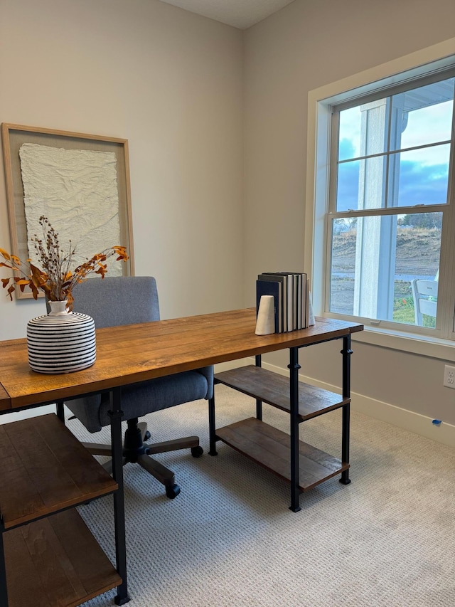 office area featuring baseboards and light carpet