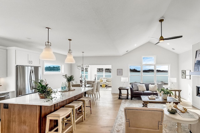 kitchen with a kitchen island, freestanding refrigerator, light wood-style floors, a glass covered fireplace, and open floor plan