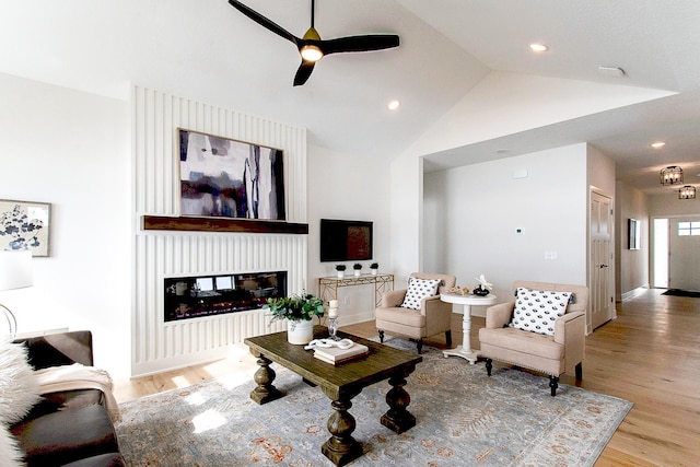 living area featuring a multi sided fireplace, a ceiling fan, lofted ceiling, and wood finished floors