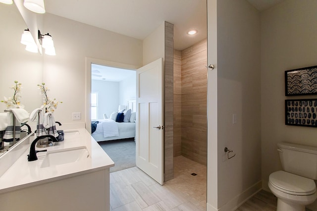 ensuite bathroom featuring toilet, a walk in shower, a sink, ensuite bath, and double vanity