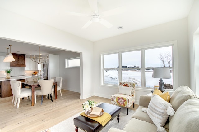 living room featuring light wood-type flooring, baseboards, and a ceiling fan