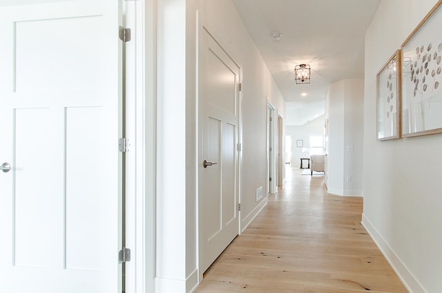 hallway featuring light wood-style flooring and baseboards