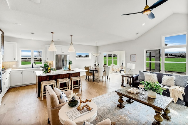 living room featuring light wood-type flooring, ceiling fan, and vaulted ceiling