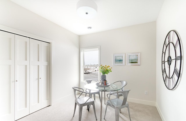 dining room featuring light colored carpet and baseboards