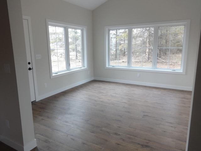 unfurnished room with baseboards, lofted ceiling, and wood finished floors