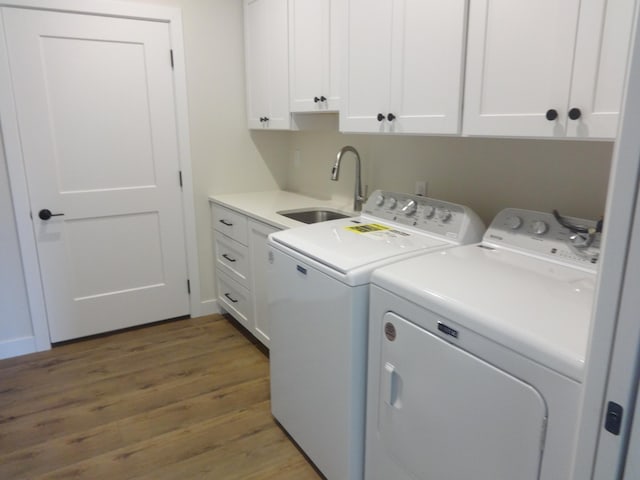 laundry room with cabinet space, washer and dryer, wood finished floors, and a sink