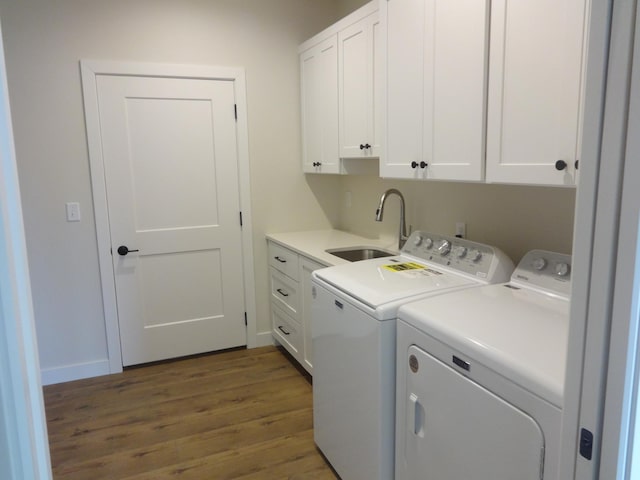 laundry area featuring a sink, washer and dryer, wood finished floors, cabinet space, and baseboards